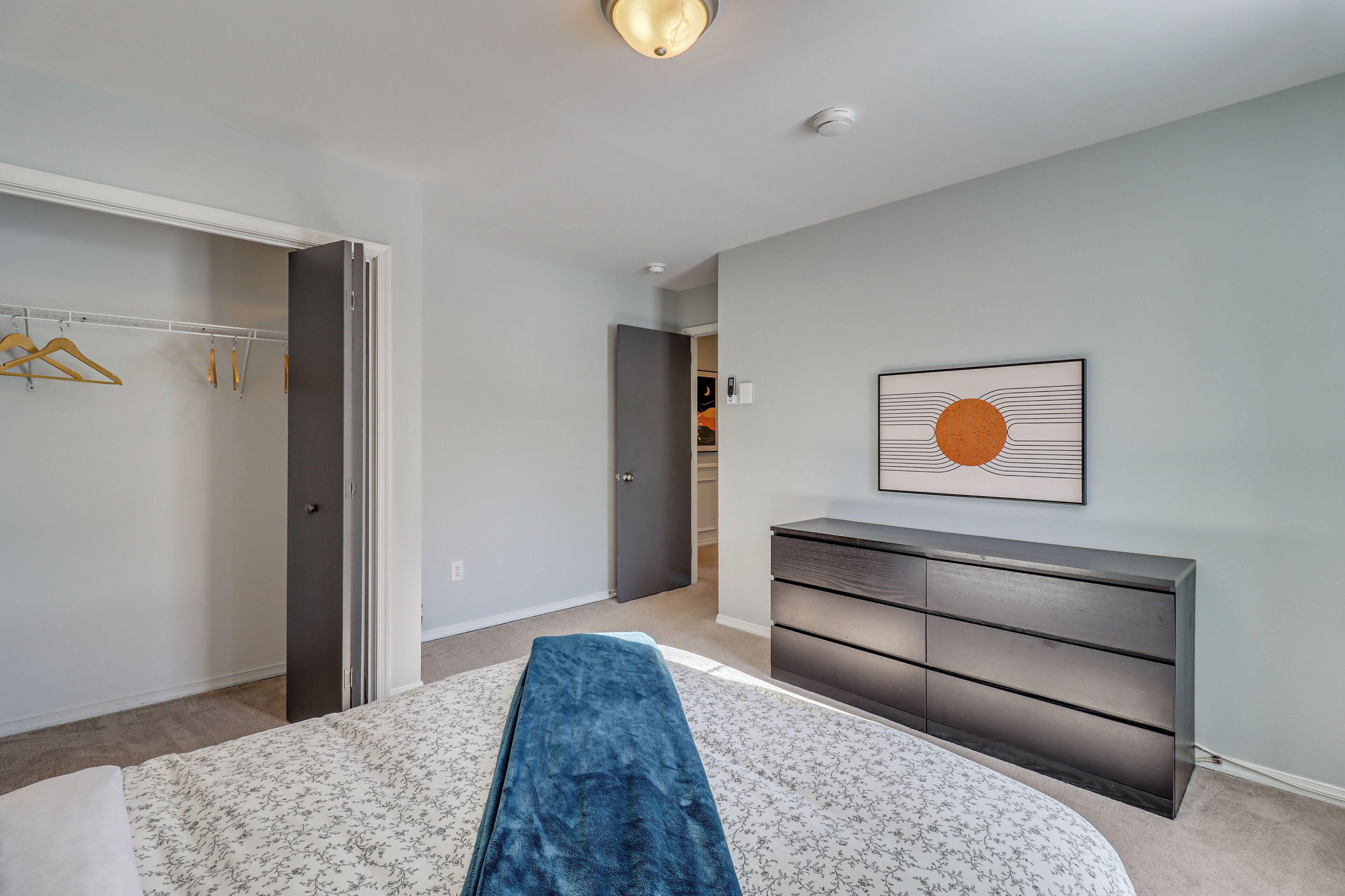Une chambre à coucher comprenant un lit, une commode, un placard et un couloir menant à une autre pièce.