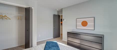 Une chambre à coucher comprenant un lit, une commode, un placard et un couloir menant à une autre pièce.
