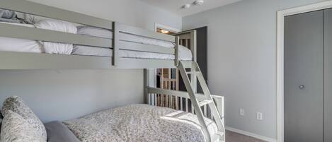 Una cama litera con escalera, una ventana pequeña y una puerta a un armario.