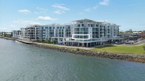 Un hôtel moderne à plusieurs étages, avec vue sur le port, doté de balcons et d’une façade en verre.