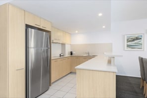 A modern kitchen with light wood cabinets, a stainless steel refrigerator, and a white countertop. - River`s Edge Retreat - Premium Suite (Ballina)