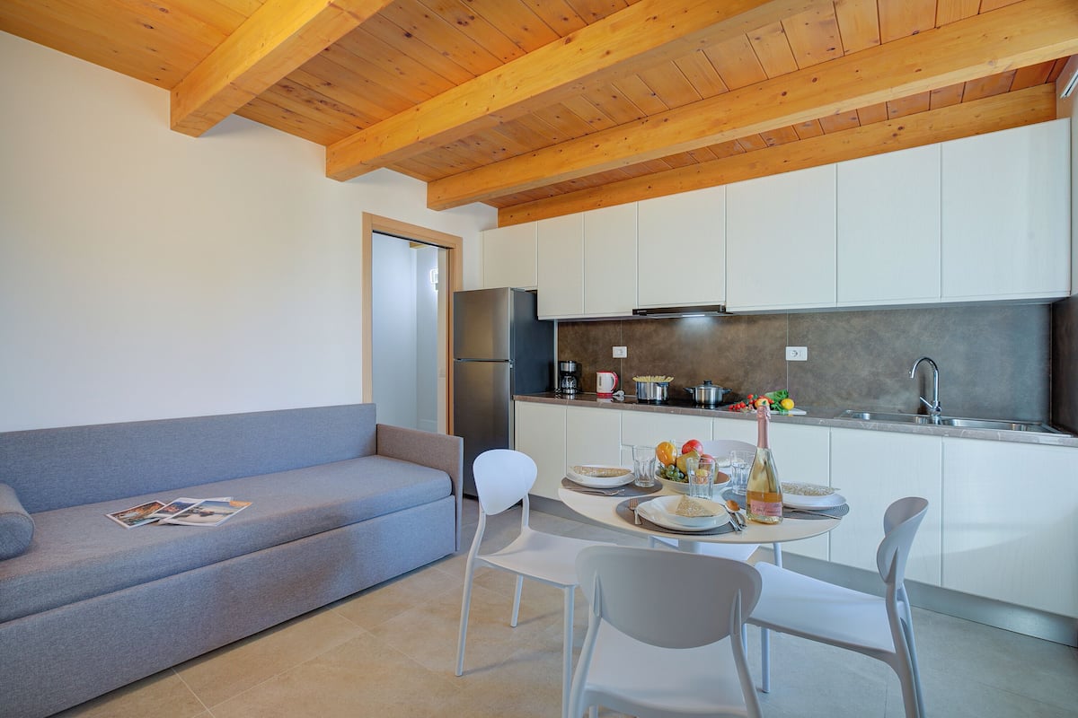A modern kitchen with white cabinets, a built-in oven, and a stainless steel refrigerator.