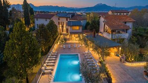 A residential property with a swimming pool, lounge chairs, and a view of mountains. - Residenza Lugana Apartments (Peschiera del Garda)