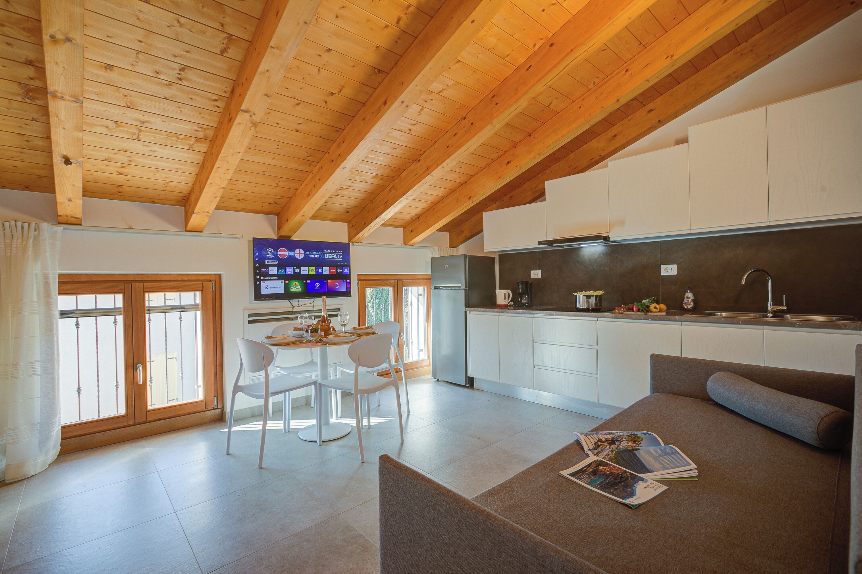 A modern kitchen with white cabinets, a stainless steel refrigerator, and a built-in oven.