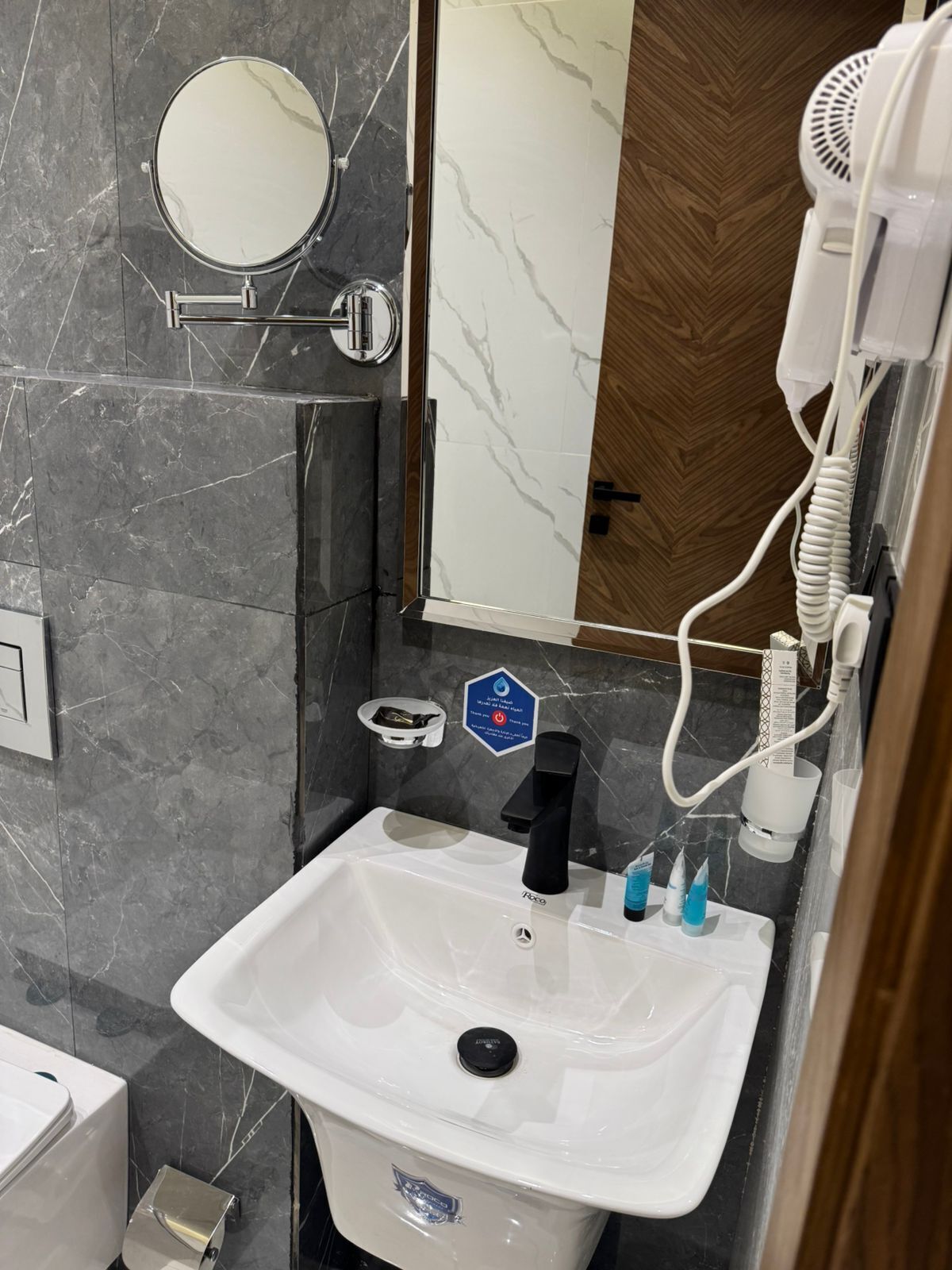 A bathroom with a white sink, a mirror, a hairdryer, and a towel rack.