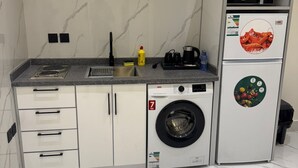 Μια μικρή, λειτουργική κουζίνα με εντοιχισμένο πλυντήριο ρούχων, φούρνο μικροκυμάτων και ψυγείο.