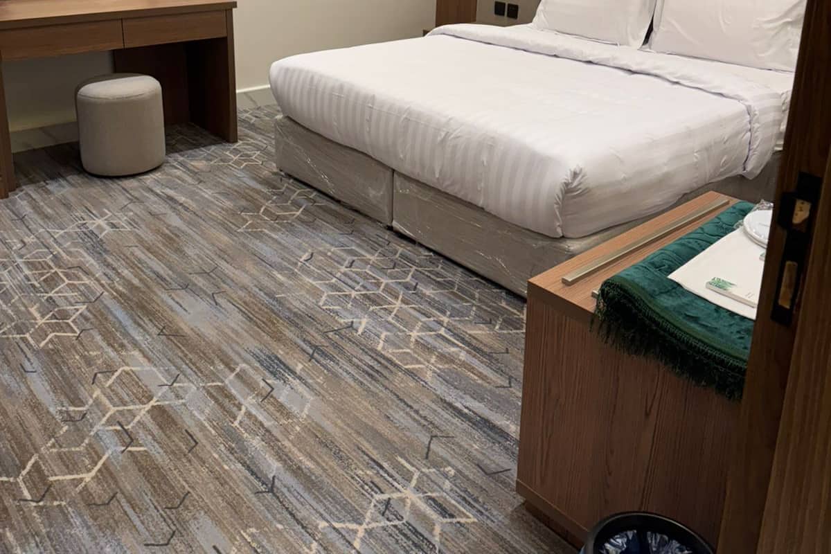Una habitación de hotel moderna con cama, escritorio de madera, espejo y un cesto de basura.