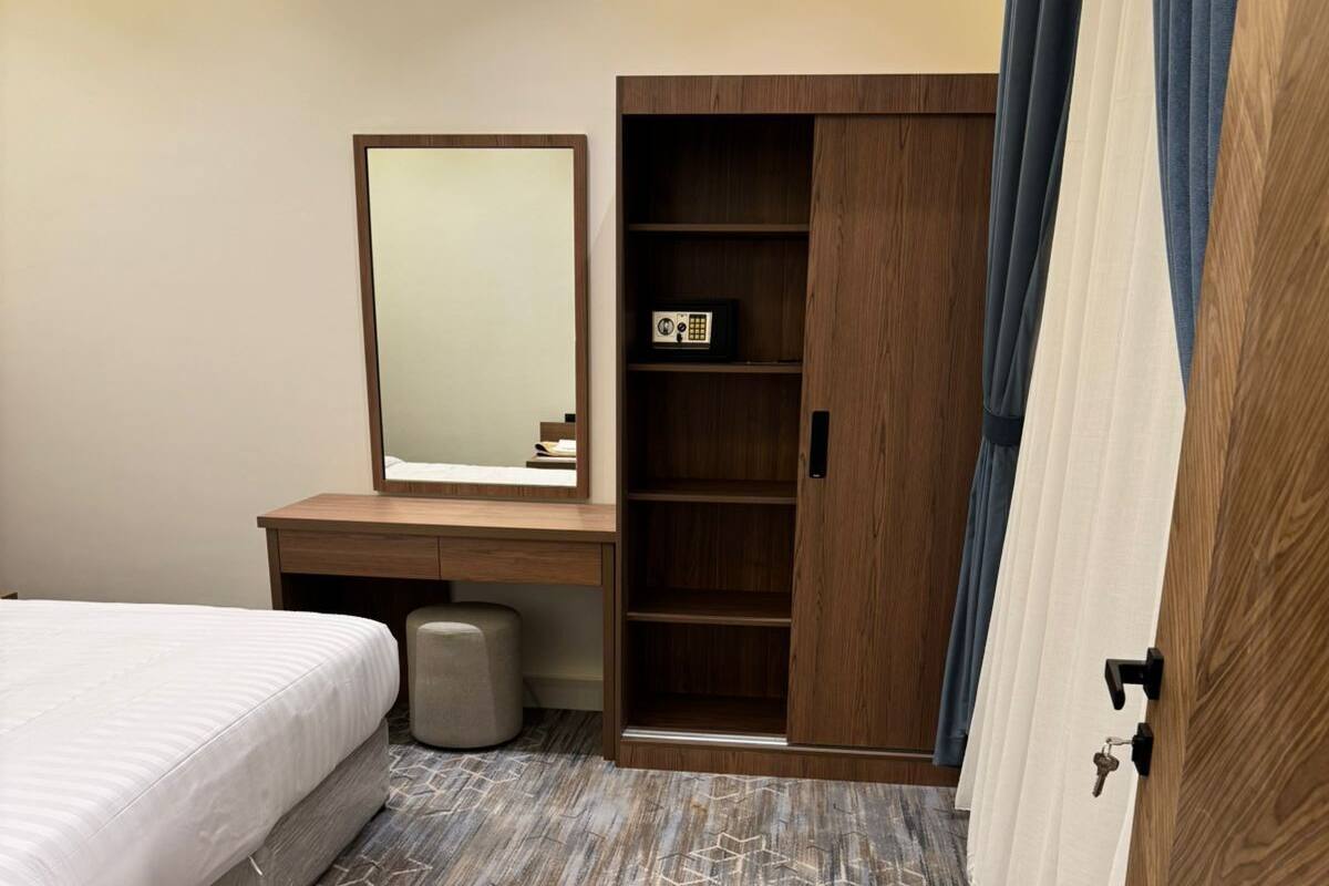 Una habitación de hotel con cama, escritorio con espejo, armario y piso con diseño.