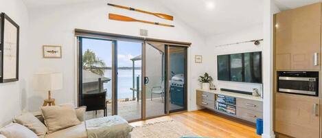 A modern living room with a sofa, a television, and a sliding glass door leading to an outdoor area.