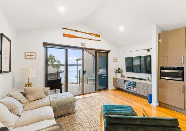 A modern living room with a sofa, a television, and a sliding glass door leading to an outdoor area.