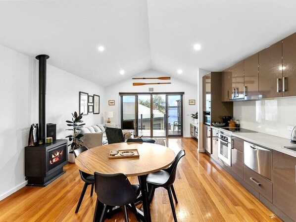 Una cocina moderna con electrodomésticos de acero inoxidable, un comedor con mesa redonda y un estufa de leña.
