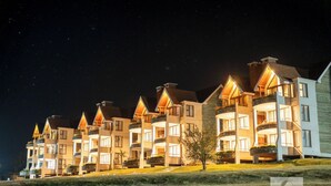 Una hilera de edificios de varios pisos con balcones, iluminados por la noche.