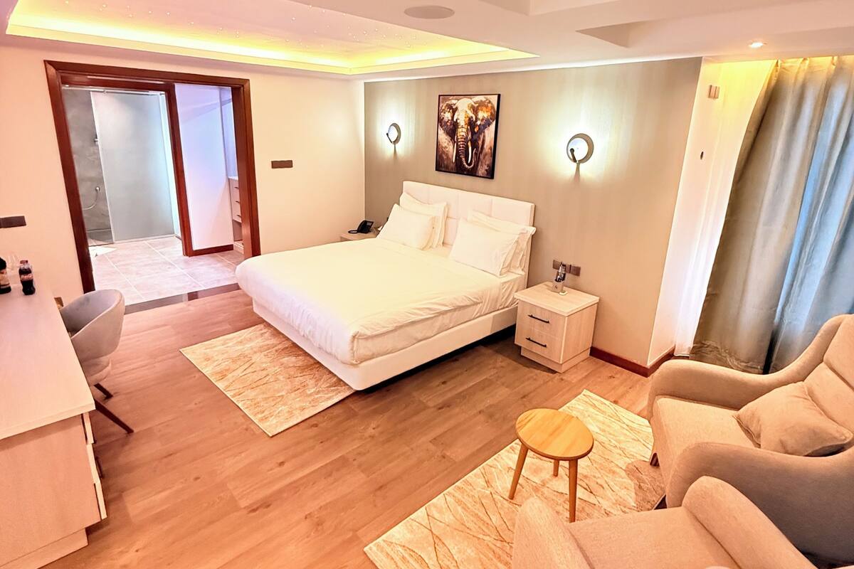 A modern bedroom with a large bed, bedside tables, a desk, and a chair.