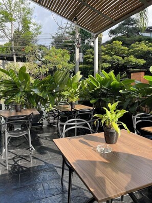 An outdoor patio with tables and chairs, surrounded by potted plants. - BH Poblado (Medellín)