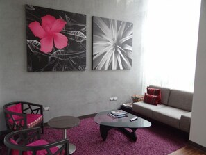 A living room with a sofa, two chairs, a coffee table, and two wall art pieces.