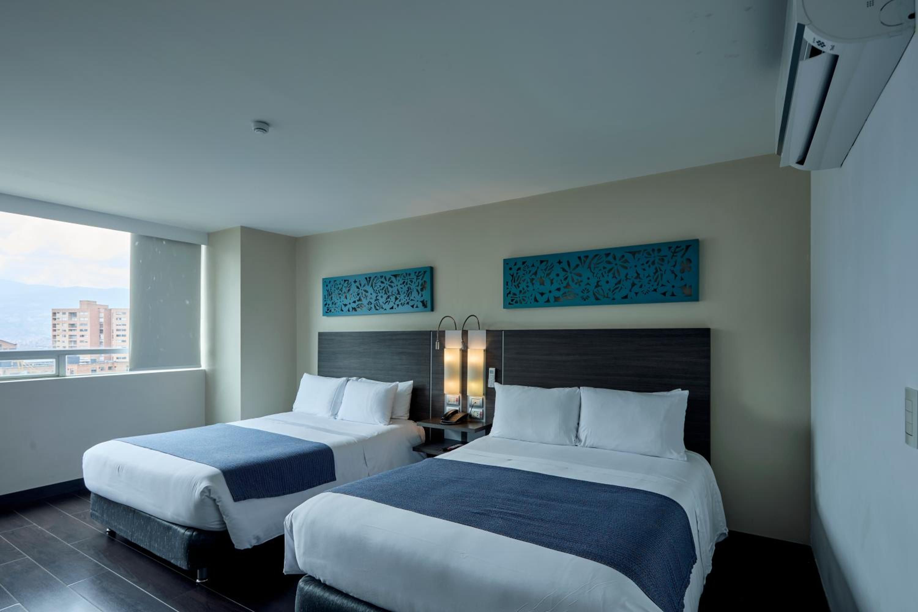 Una habitación de hotel con dos camas, un ventanal grande y decoración mural.
