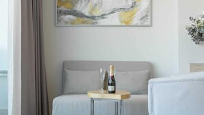 A hotel room with a bed, a small round table with a bottle of champagne and a glass, and a painting on the wall. - La Sort Hotel (Teulada)