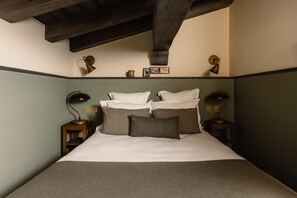 A bed with white linens, two bedside tables with lamps, a wooden headboard, and a shelf with decorative items. - Le Fitz Roy (Les Belleville)