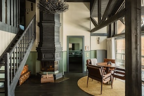 A room with a fireplace, a staircase, a dining area with chairs, and a view through a window. - Le Fitz Roy (Les Belleville)