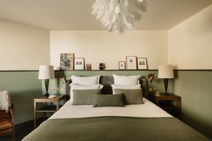A neatly arranged hotel room with a bed, two bedside tables, lamps, and framed pictures on the wall. - Le Fitz Roy (Les Belleville)