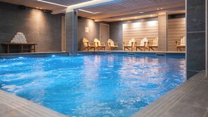 An indoor swimming pool with wooden chairs and a stack of towels. - Le Fitz Roy (Les Belleville)