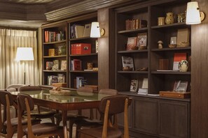 A library with bookshelves, a glass table, and wooden chairs. - Le Fitz Roy (Les Belleville)