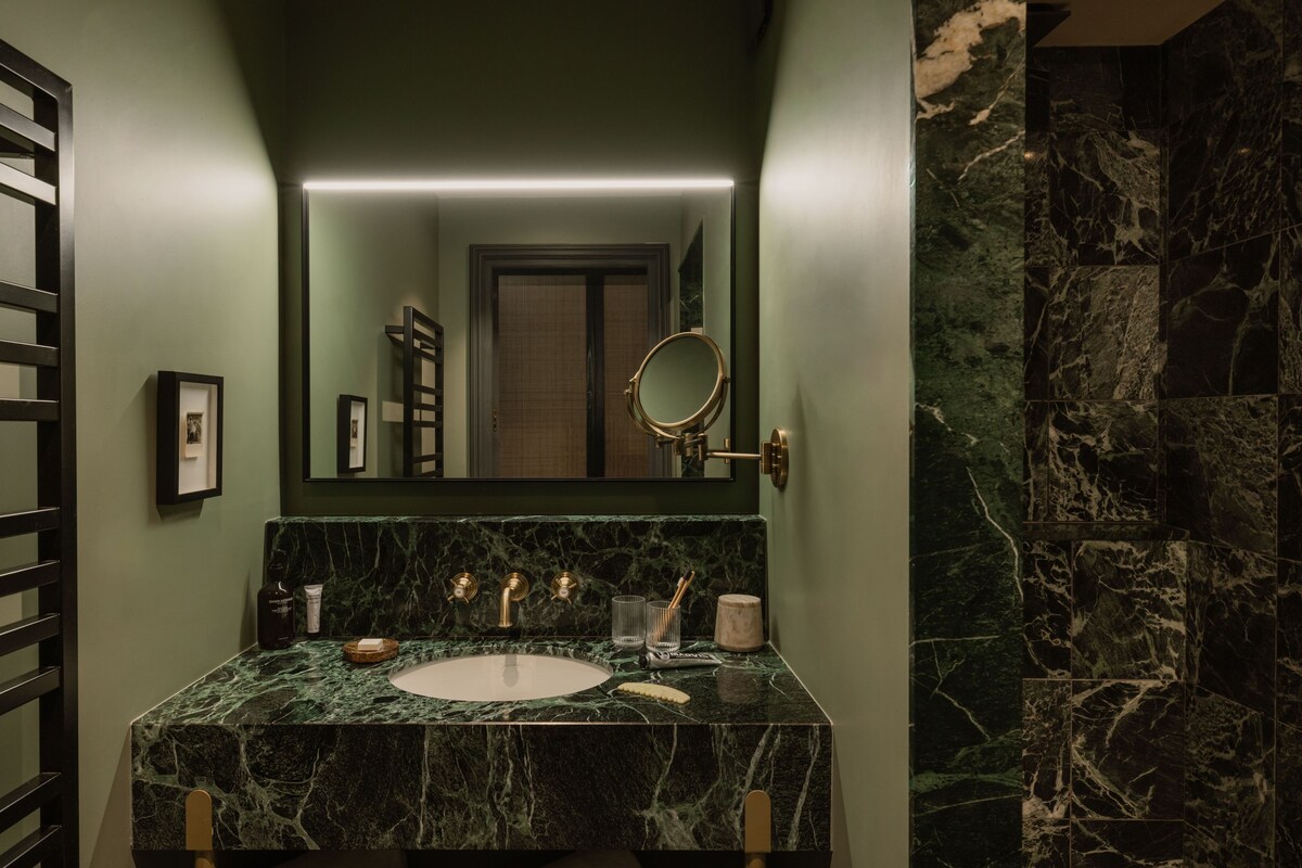 A bathroom with a marble sink, a mirror, and a framed picture on the wall.