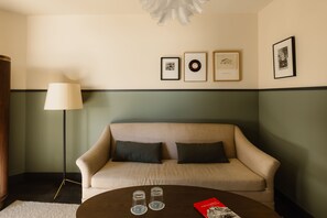 A room with a sofa, a coffee table with glasses and a book, and framed pictures on the wall. - Le Fitz Roy (Les Belleville)