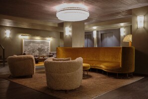 A modern lobby with a large chandelier, a sofa, and two armchairs. - Le Fitz Roy (Les Belleville)