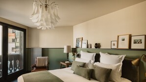 Une chambre d’hôtel avec un grand lit, une chaise, un bureau, une lampe et des tableaux encadrés au mur.