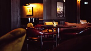 Un coin bar à la lumière tamisée, avec des sièges en cuir, une table sur laquelle se trouve une chope et des œuvres d’art encadrées accrochées aux murs.