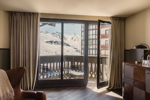 A room with a large window, a wooden desk, a chair, and a view of snow-covered mountains. - Le Fitz Roy (Les Belleville)