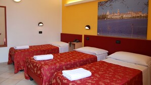 Ein Hotelzimmer mit zwei Einzelbetten, jeweils mit roter Bettdecke und weißen Kissen, einem Nachttisch mit Telefon und einer wandmontierten Lampe.