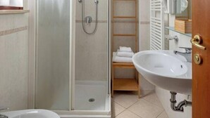 Ein Badezimmer mit Duschkabine, Waschbecken und Spiegel.