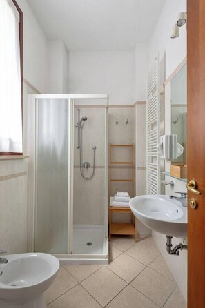 Une salle de bain avec une douche à parois de verre, un lavabo et un miroir.