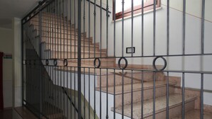 A staircase with a metal railing, carpeted steps, and a small window with a wooden frame. - ABC Comfort Hotel Mantua City Centre (Mantua)