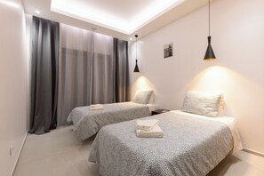 Een slaapkamer met twee bedden, een dakraam en hanglampen.