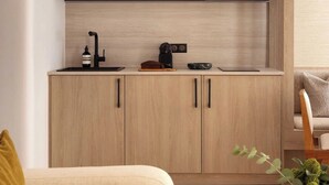 Een moderne keuken met houten kastjes, een zwarte magnetron en een koffieapparaat.