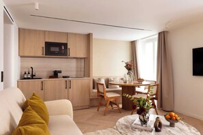 A modern living room with a sofa, coffee table, and a dining area with a table and chairs. - Superb Air-conditioned Apartment - Le Marais (Paris)