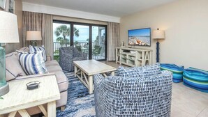 A room with a sofa, armchair, table, and a TV on a stand. - Gulf-Front Grandeur: Your Private 2BR Beachfront Sanctuary at Villa 2628 (Captiva)