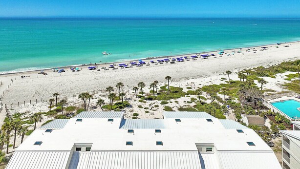 A beach view with a pool, palm trees, and a clear sky. - Gulf-Front Grandeur: Your Private 2BR Beachfront Sanctuary at Villa 2628 (Captiva)