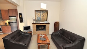 Una sala de estar con dos sofás de cuero, una mesa de centro de madera, un televisor, una chimenea y un reloj en la pared.