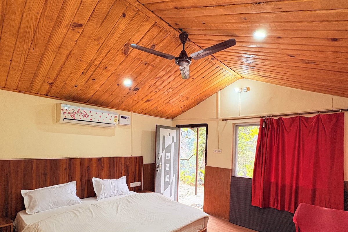 Un dormitorio con techo de madera, una cama, una mesa y una silla.