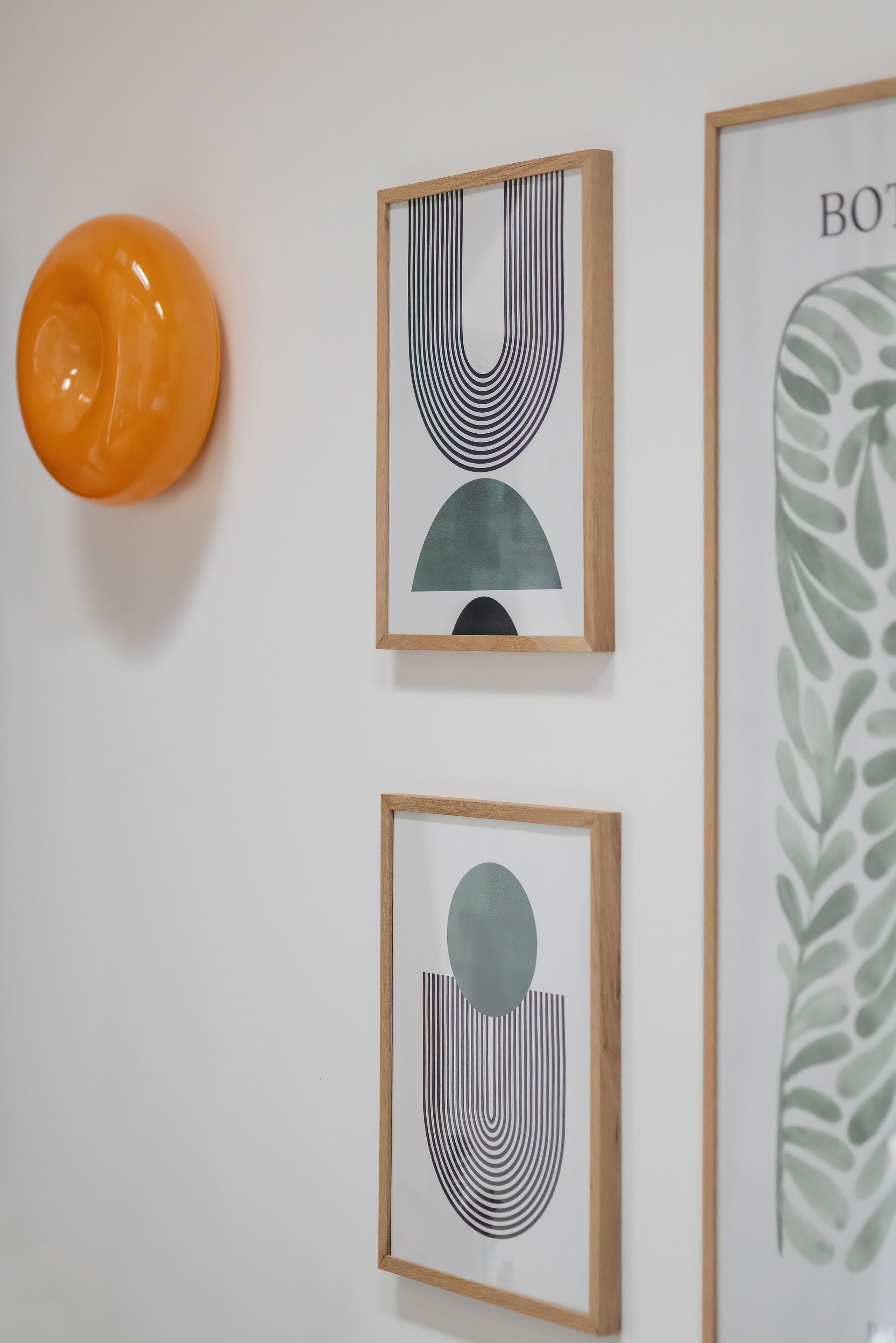 A wall with three framed artworks and a single orange object.