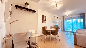 Ein modernes Wohnzimmer mit Essbereich, einem weißen Sofa, einem Fernseher und einem Balkon mit Blick.