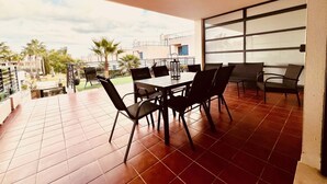Patio esterno con tavolo e sedie, vista sulla città e pavimento piastrellato.