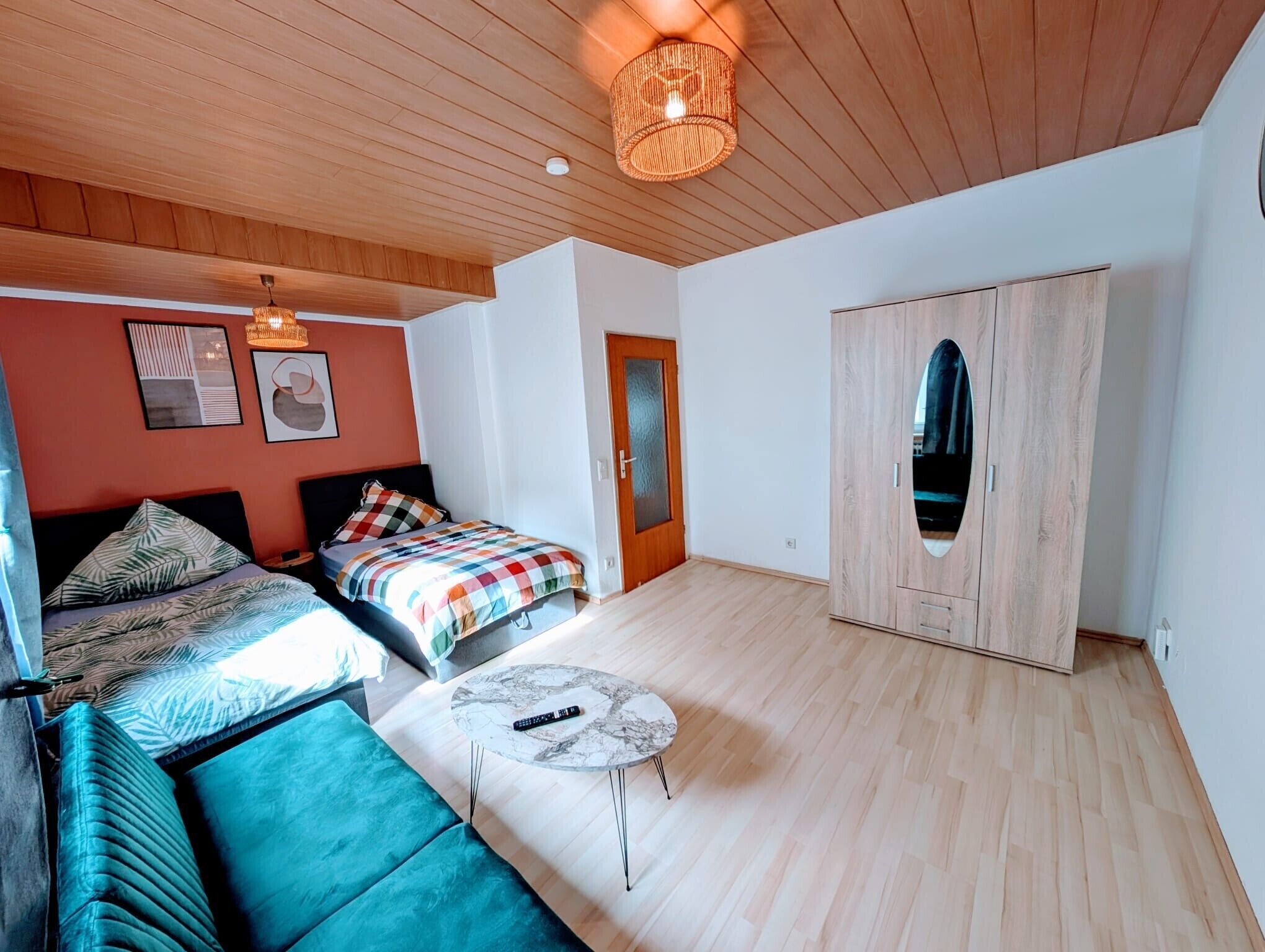 Un dormitorio con cama, sofá, una mesita redonda, armario y una lámpara en el techo.