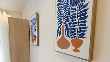 Un pasillo con dos cuadros enmarcados en la pared, una puerta de madera y una cesta de mimbre en el suelo.