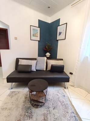 Un salon moderne avec un canapé noir, une table basse ronde et un mur d’accent bleu.