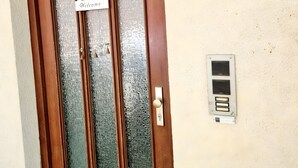 A wooden door with a frosted glass panel, a welcome sign, a wall-mounted light fixture, and a doorbell.